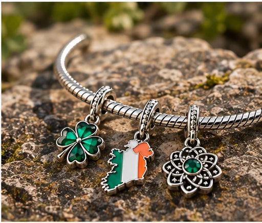 The three charms on a mossy rock: a green shamrock, an Ireland map in green, white and orange, and a flower-shaped charm with a green stone